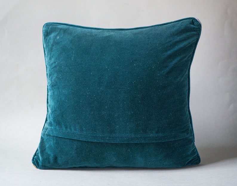 May include: A teal blue velvet pillow with a seam down the center.