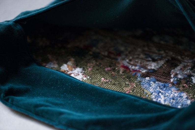 May include: A teal velvet pouch with a colorful woven fabric lining. The pouch is open and the lining is visible.