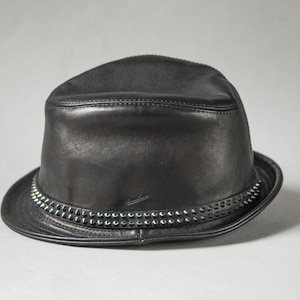 May include: A black leather fedora hat with a studded band around the brim. The hat has a classic, structured shape and a slightly curved brim. The hat is a stylish accessory.