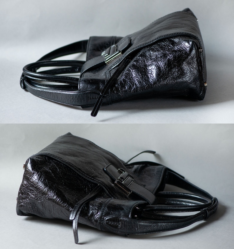 Op de afbeelding: Zwarte leren tote bag met een zilveren gespsluiting en een bovenste handvat. De tas heeft een gestructureerde, gepunte lederen afwerking.