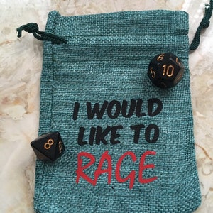 May include: A teal green drawstring bag with the text "I would like to RAGE" printed on it. The bag contains three black dice with gold numbers.