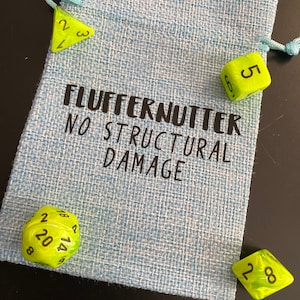 May include: A blue drawstring bag with the text "FLUFFERNUTTER NO STRUCTURAL DAMAGE" printed on it. The bag contains four green dice with black numbers.