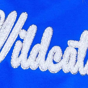 May include: White embroidered "Wildcats" lettering on a royal blue background.
