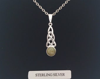 Può includere: Una collana d'argento con un ciondolo a nodo celtico e una pietra verde. Il ciondolo è su uno sfondo nero con le parole "STERLING SILVER" stampate sotto.