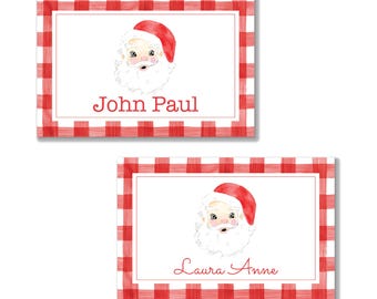 May include: Two rectangular Christmas gift tags with a red and white gingham border. Each tag features a watercolor illustration of Santa Claus and a name in red script: "John Paul" and "Laura Anne".