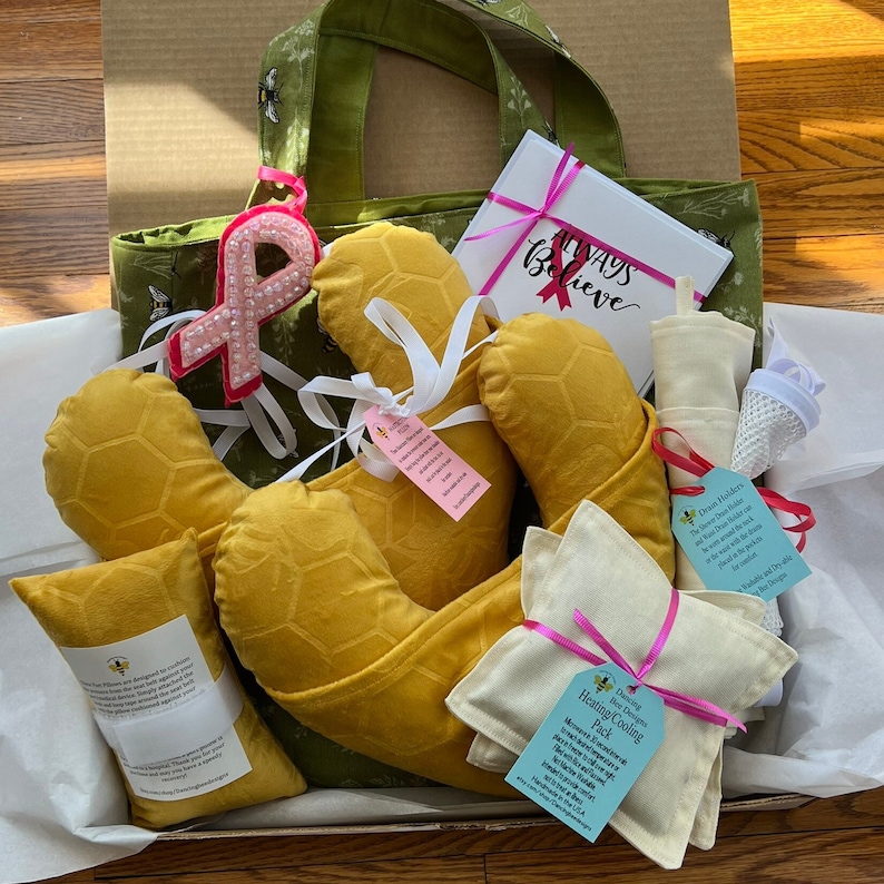Pode incluir: Um conjunto de presente contendo uma sacola verde com padr&otilde;es de abelhas, uma caixa branca com o texto Always Believe, almofadas amarelas com textura de favo de mel, uma bolsa t&eacute;rmica creme e um suporte de drenagem com fitas.