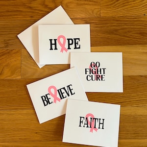Pode incluir: Quatro cart&otilde;es de felicita&ccedil;&otilde;es retangulares brancos com texto preto e la&ccedil;os cor-de-rosa de consciencializa&ccedil;&atilde;o. Os cart&otilde;es exibem as palavras HOPE, GO FIGHT CURE, BELIEVE e FAITH. Cada cart&atilde;o incorpora um s&iacute;mbolo de la&ccedil;o rosa no design.