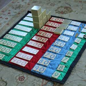 May include: A set of wooden number blocks and rods for learning math. The blocks are arranged in a staircase pattern, with the largest block at the top and the smallest block at the bottom. The blocks are labeled with the numbers 100, 200, 300, 400, 500, 600, 700, 800, 900, and 1000. The rods are labeled with the numbers 1, 2, 3, 4, 5, 6, 7, 8, 9, and 10.