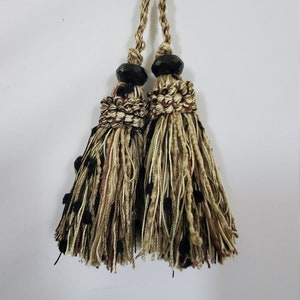 May include: Two brown and black tassel tiebacks with black beads. The tassels are made of a mix of brown, black, and cream colored threads.