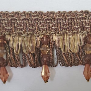 May include: Brown and gold woven trim with a fringe and dangling crystal beads.