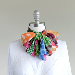 A bright colored patchwork print chiffon oblong scarf with a hot pink stripe on one side.