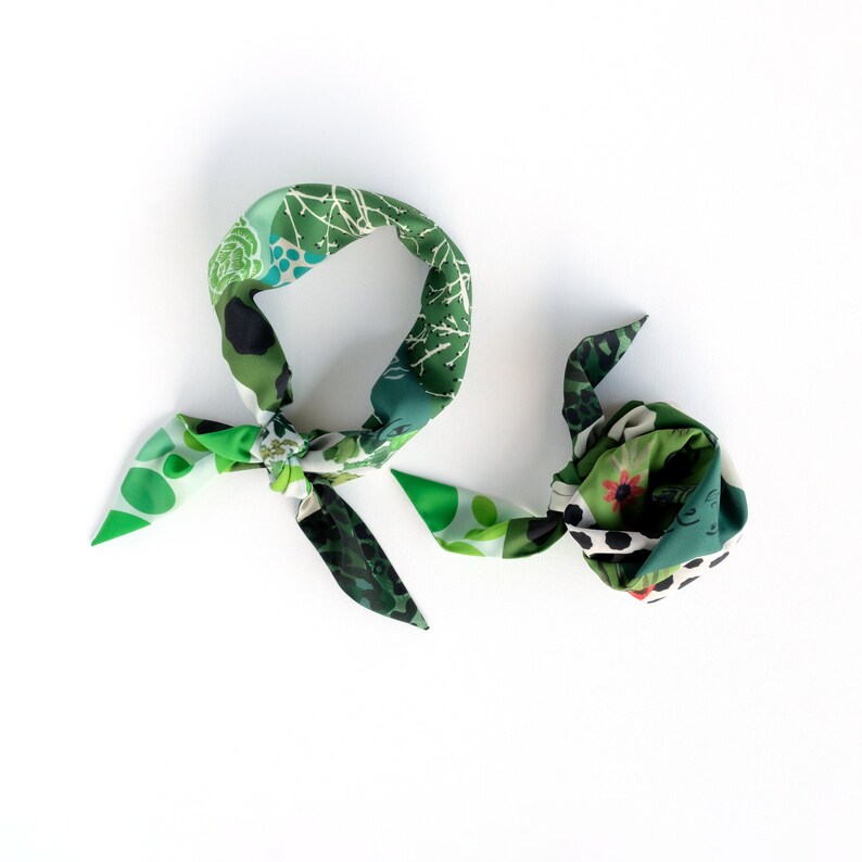 A flat-lay photo of two green patchwork print triangle scarves rolled and tied as neckerchiefs.