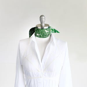 Small soft triangle scarf in a fun medley of green prints. Shown tied as a choker scarf.