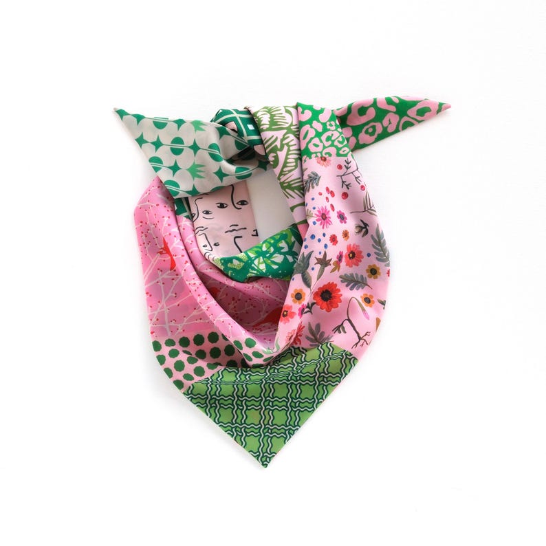 May include: A colorful silk scarf with a patchwork design. The scarf features sections of pink, green, and white with various patterns, including floral, geometric, and abstract face designs. The scarf is tied in a knot.