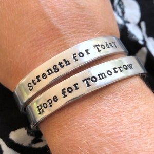 May include: Two silver bracelets with the words "Strength for Today" and "Hope for Tomorrow" engraved on them.