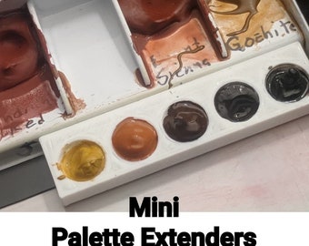 May include: A white plastic palette with six empty wells for watercolor paint. The wells are labeled "Burnt Sienna" and "Goethite". The palette is labeled "Mini Palette Extenders".
