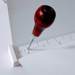Bookbinding punch signature cradle with awl.