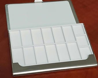 May include: A silver metal case with a white plastic tray containing 16 compartments. The case is open and the tray is visible.