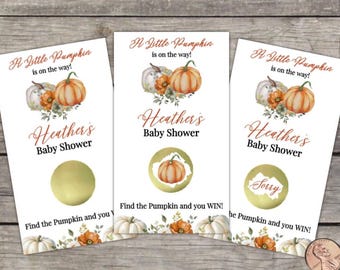 May include: Three baby shower scratch-off cards with a pumpkin theme. Each card has the text "A Little Pumpkin is on the way!" and "Heather's Baby Shower." One card says "Sorry" in the scratch-off area. The cards are on a wooden surface.