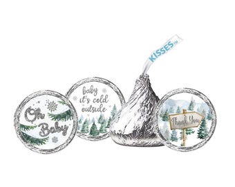 May include: A silver foil-wrapped chocolate candy with three circular stickers. The stickers feature winter-themed designs with text that reads "Oh Baby", "baby it's cold outside", and "Thank You".