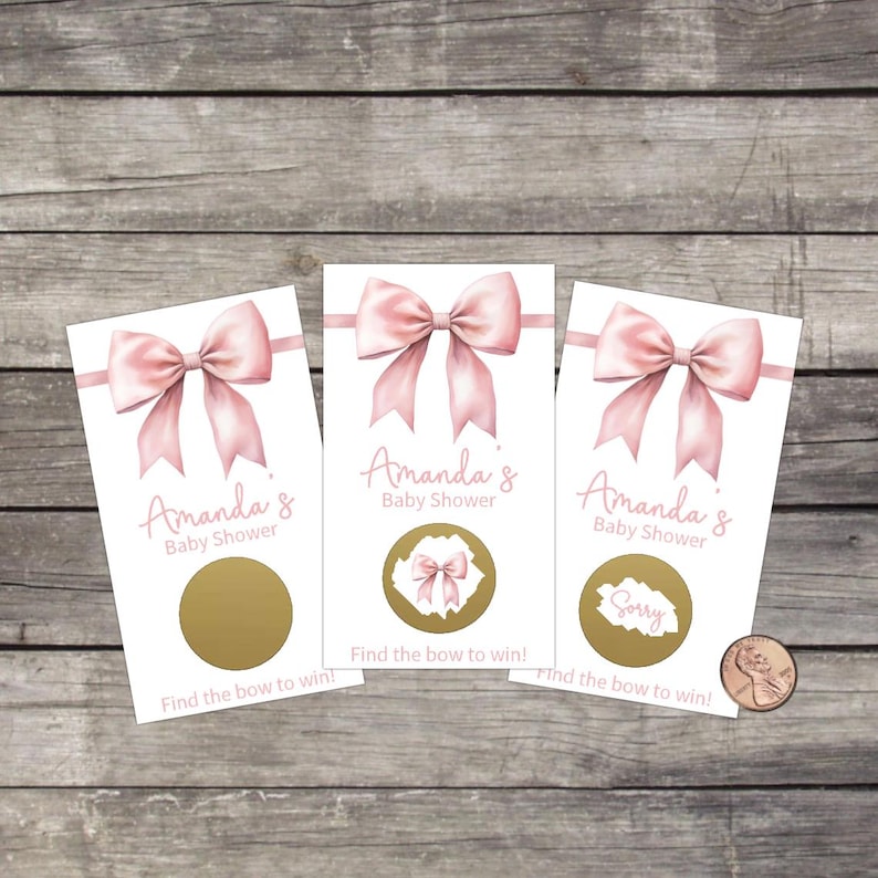 May include: Three white baby shower scratch-off cards with a pink bow design. The cards read "Amanda's Baby Shower" and "Find the bow to win!" One card has a "Sorry" message. A penny is next to the cards.
