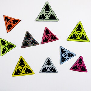 May include: Ten colourful triangular patches with a black biohazard symbol in the centre. The patches are in various colours including yellow, green, orange, pink, blue, and white.