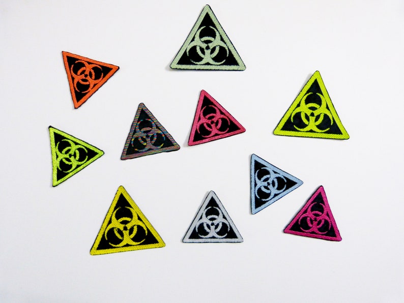 May include: Ten colourful triangular patches with a black biohazard symbol in the centre. The patches are in various colours including yellow, green, orange, pink, blue, and white.