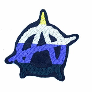 Puede incluir: Un parche bordado en forma de símbolo de anarquía con un esquema de color amarillo, blanco, azul y negro.