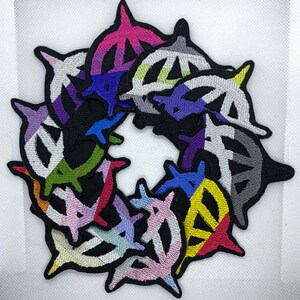 May include: A set of 10 embroidered iron-on patches featuring a stylized symbol in various colours, including black, white, red, yellow, green, blue, purple, and pink.