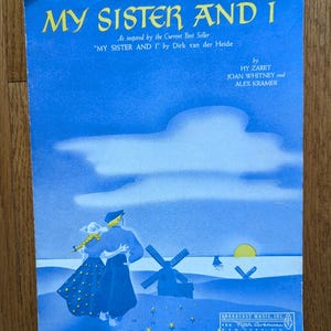 May include: A vintage sheet music cover for the song "My Sister and I" inspired by the book "My Sister and I" by Dirk van der Heide. The cover features a blue sky with clouds, a couple walking on a beach, and windmills in the distance.