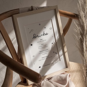 May include: A framed printable sign with a drinks menu featuring a handwritten title "Drinks" with a list of beer, wine, signature cocktails, and non-alcoholic options. The sign is decorated with small stars and shooting stars.