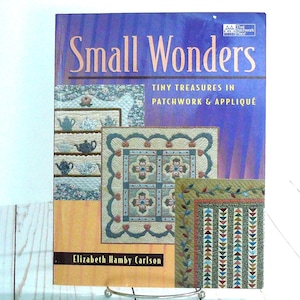 May include: A book titled "Small Wonders" with the subtitle "Tiny Treasures in Patchwork & Appliqué." The cover features images of quilts and teacups. The author's name, Elizabeth Hamby Carlson, is also visible.