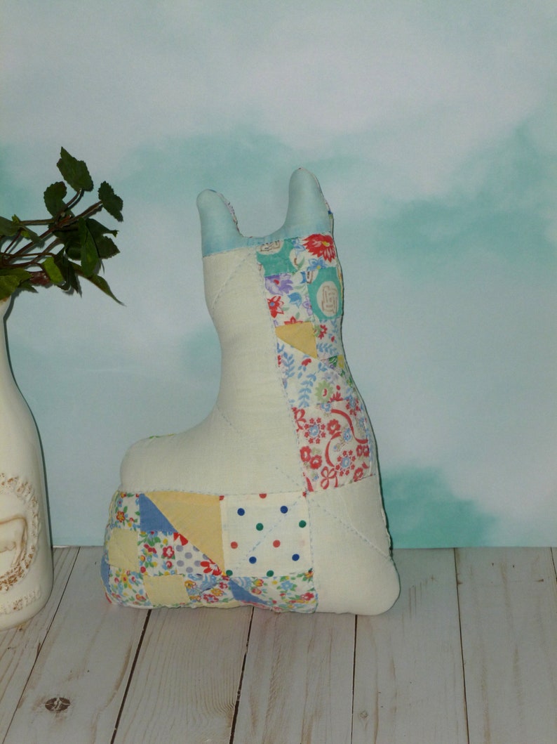 May include: A patchwork fabric llama toy with a white base and colorful fabric squares. The llama is standing on a light wood surface.