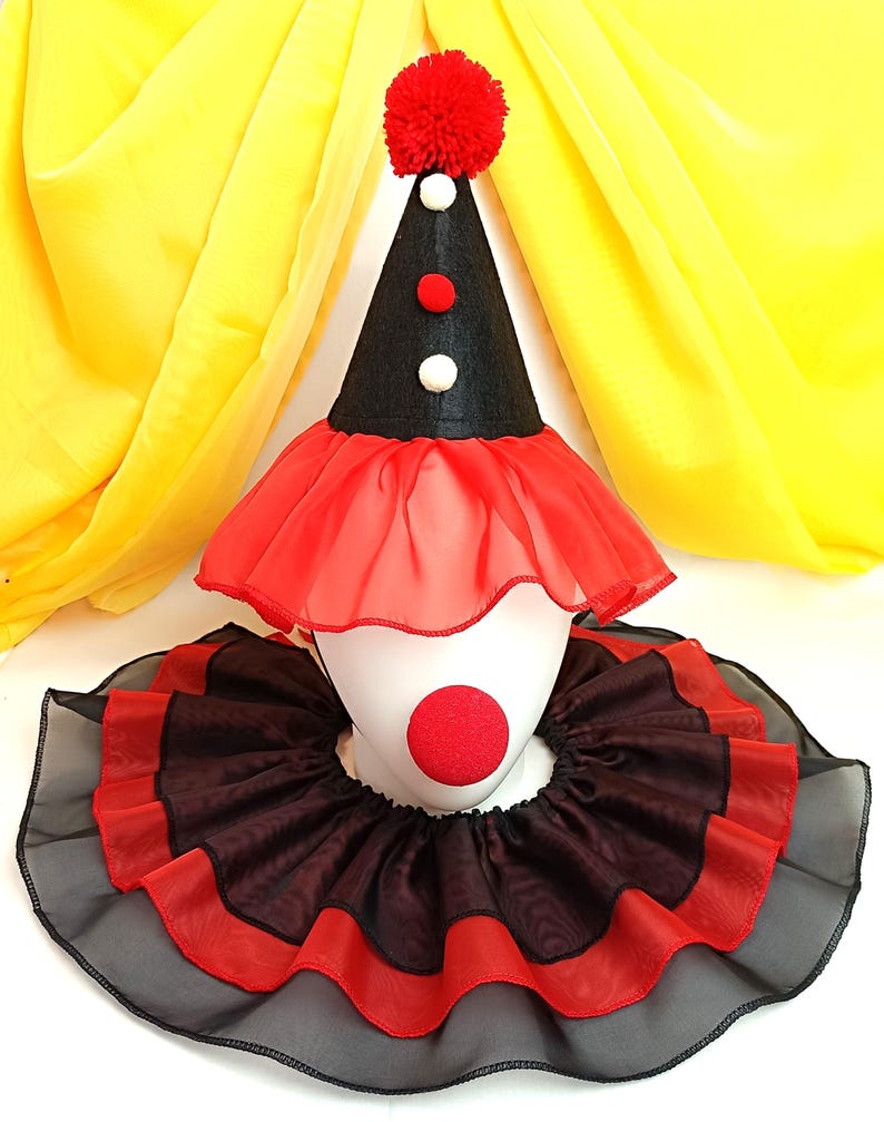 May include: A red and black clown costume hat with a red pom-pom on top. The hat has a red and black ruffle around the bottom. A red and black ruffle collar is also included.