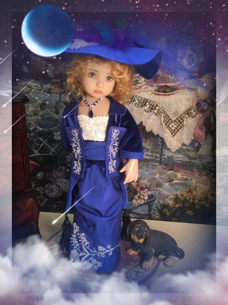 May include: A porcelain doll wearing a blue velvet dress with white embroidery and a blue hat. The doll has blonde hair and blue eyes. The doll is standing on a white cloud-like surface with a small brown and black dog figurine beside it.