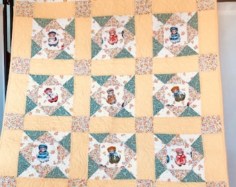 May include: A handmade quilt with a patchwork design. The quilt features a repeating pattern of squares with images of children in vintage clothing, surrounded by floral and geometric patterns in shades of yellow, white, and green.