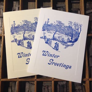 May include: Two blank greeting cards with a blue ink illustration of a winter scene with people walking in a snowy park. The text on the cards reads "Winter Greetings" and "Winter".