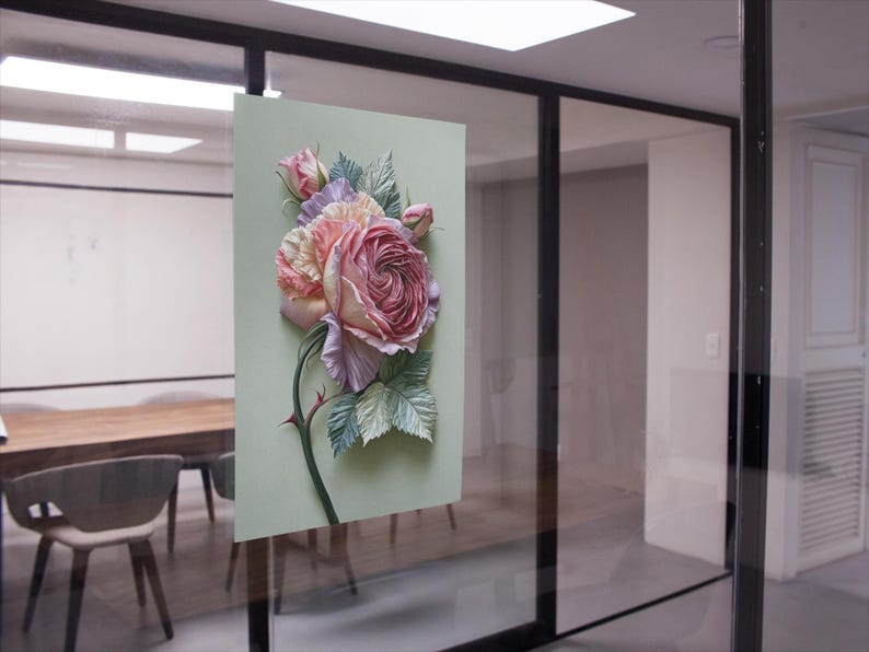 May include: A floral artwork featuring a large, detailed rose in shades of pink, peach, and lavender, with green leaves and a thorny stem. The artwork is mounted on a light green background, creating a three-dimensional effect.
