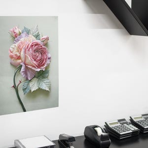 May include: A floral print on a rectangular canvas. The artwork features a large, detailed rose in shades of pink and peach, with green and blue-grey leaves. The rose is the focal point, with a dark green stem and thorns.