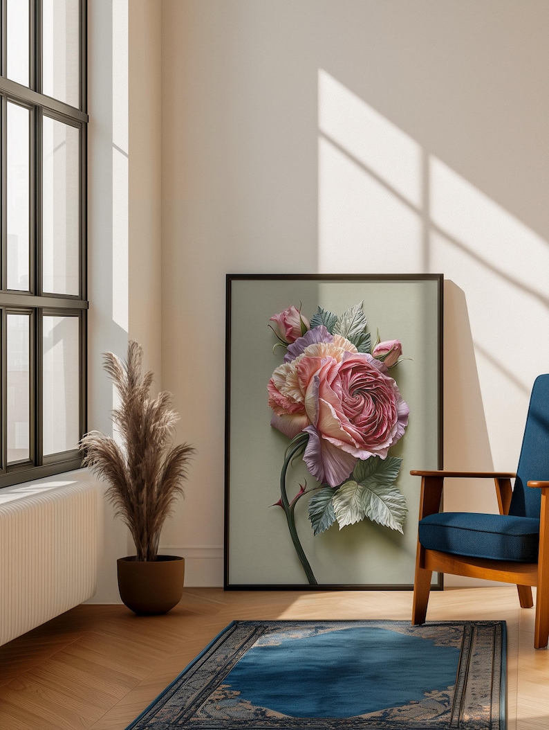 May include: A framed floral art print featuring a large, detailed rose in shades of pink, lavender, and cream. The artwork is set against a soft green background, with a black frame. The image is displayed in a well-lit room with a blue chair and a decorative rug.