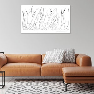 May include: A black and white line drawing of several pairs of legs and feet. The artwork is displayed on a white rectangular canvas, mounted on a gray wall above a brown leather sofa and ottoman. The room also features a black side table.
