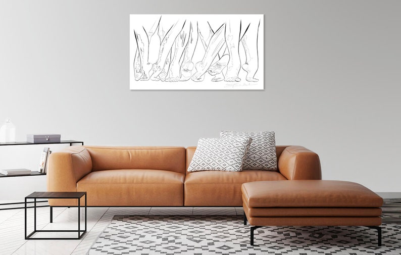 May include: A black and white line drawing of several pairs of legs and feet. The artwork is displayed on a white rectangular canvas, mounted on a gray wall above a brown leather sofa and ottoman. The room also features a black side table.