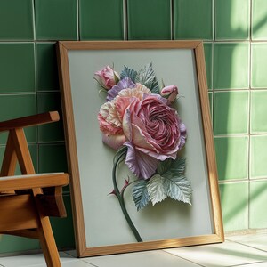 May include: A framed floral art print featuring a large, detailed rose in shades of pink, lavender, and cream. The artwork is set against a light green background and framed in natural wood. The image is leaning against a green tiled wall.