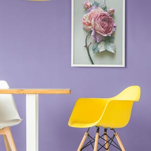 May include: A framed floral art piece featuring a large, detailed rose in shades of pink and purple, with green leaves and a thorny stem. The artwork hangs on a purple wall, with a yellow chair and lamp in the foreground.