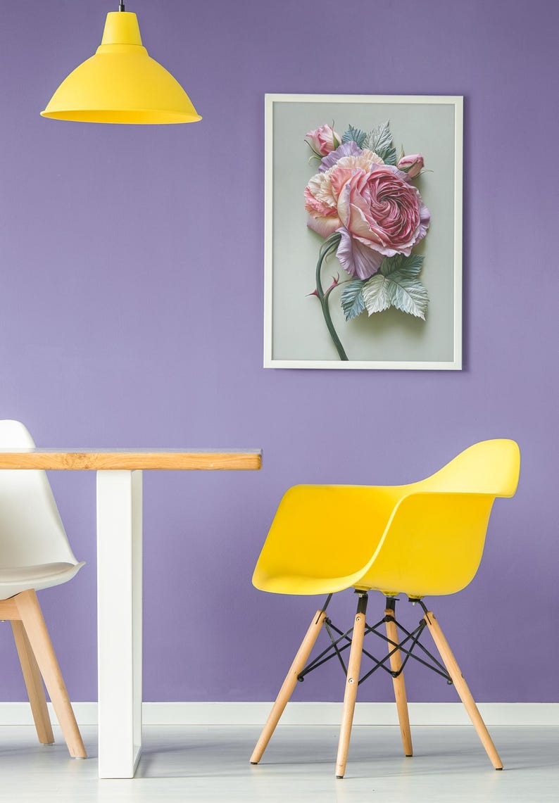 May include: A framed floral art piece featuring a large, detailed rose in shades of pink and purple, with green leaves and a thorny stem. The artwork hangs on a purple wall, with a yellow chair and lamp in the foreground.