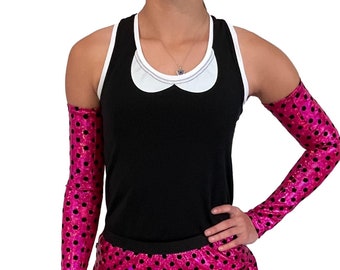 May include: A pink and black polka dot skirt with a black waistband. The skirt is made of a shiny material and has a ruffled hem.