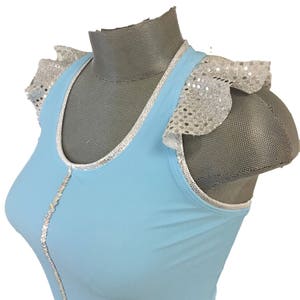 May include: A light blue sleeveless top with silver sequin trim and ruffled sleeves. The top has a scoop neck and a fitted silhouette.