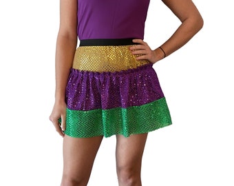 May include: A short, three-tiered skirt with gold, purple, and green sequins. The skirt is a festive and fun accessory for any occasion.