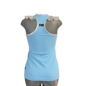 May include: A light blue sleeveless tank top with a white lace trim around the neckline. The tank top has a black logo on the back that says "Dance Girls".