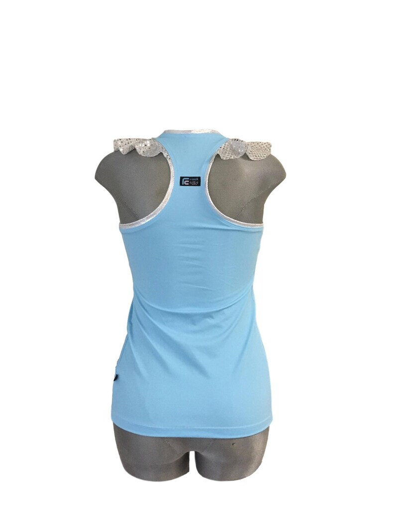 May include: A light blue sleeveless tank top with a white lace trim around the neckline. The tank top has a black logo on the back that says "Dance Girls".